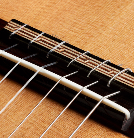 The bridge, tie-block and saddle of a 2025 Oscar Munoz classical guitar made of cedar and African rosewood