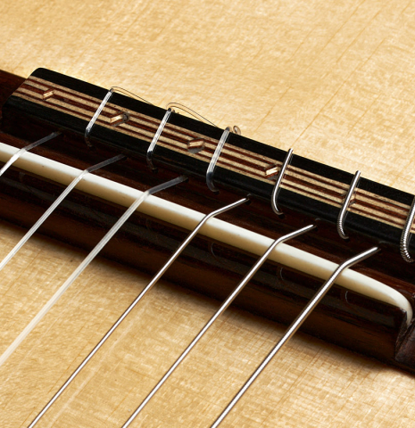 The bridge, tie-block and saddle of a 2024 Oscar Munoz classical guitar made of spruce and Makassar ebony