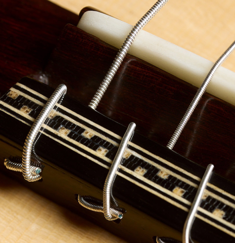 The bridge, tie-block and saddle of a 2026 Oscar Munoz classical guitar made of spruce and Makassar ebony