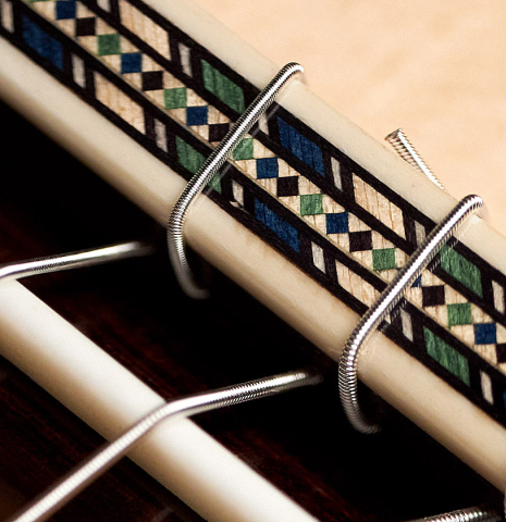 The tie-block and saddle of a 2022 Miguel Angel Gutierrez classical guitar made of spruce and Indian rosewood.