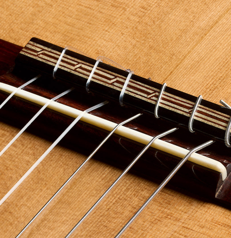 The bridge, tie-block and saddle of a 2026 Oscar Munoz classical guitar made of cedar and Makassar ebony