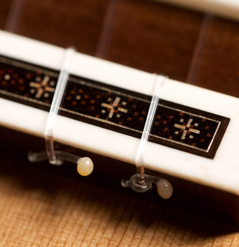 The bridge and saddle of a 2021 Darragh O'Connell classical guitar made of cedar and Indian rosewood