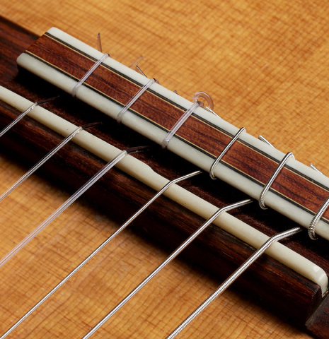 The bridge, tie-block and saddle of a 2017 David Pace "Double-Top SP/SP" classical guitar made of Sitka spruce and Indian rosewood