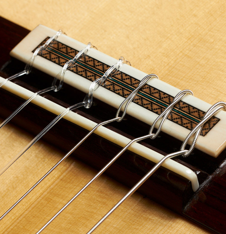 The bridge, tie-block and saddle of a 2024 Teodoro Perez "Maestro" classical guitar made of spruce and African rosewood