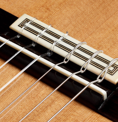 The bridge, tie-block and saddle of a 2024 Teodoro Perez "Concierto" classical guitar made of cedar and Indian rosewood.