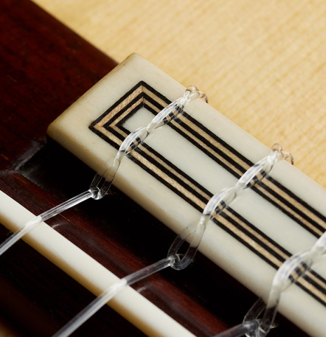 The bridge, tie-block and saddle of a 2024 Teodoro Perez "Concierto" classical guitar made of spruce and Indian rosewood