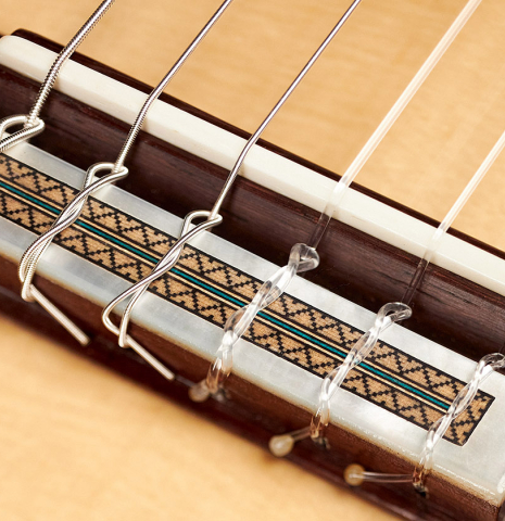 The bridge, tie-block and saddle of a 2023 Teodoro Perez "Epecial" classical guitar made of spruce and African rosewood.