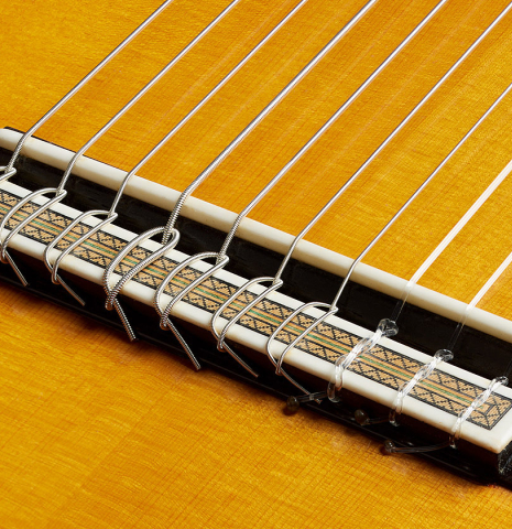 The bridge, tie-block and saddle of a 2006 Teodoro Perez "Maestro 10-string" classical guitar made of spruce and African rosewood