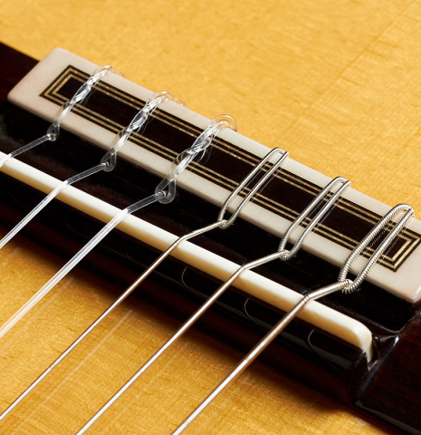The bridge, tie-block and saddle of a 2024 Teodoro Perez "Estudio C-650" classical guitar made of spruce and Indian rosewood.
