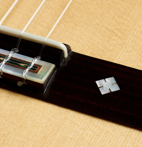 The bridge and mother-of-pearl inlay of a 2024 Teodoro Perez "1884 Torres - La Emperatriz" classical guitar made of spruce and maple