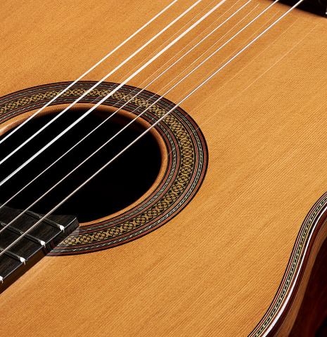 The soundboard and rosette of a 2023 Sergio Perez "Segovia" model of classical guitar made of cedar and green ebony. 