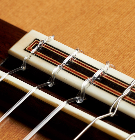 The bridge, tie-block and saddle of a 2023 Sergio Perez "Segovia" model of classical guitar made of cedar and green ebony. 