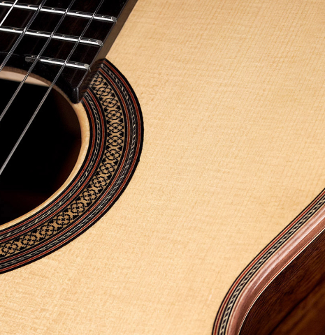The soundboard and rosette of a 2023 Sergio Perez "Segovia" model of classical guitar made of spruce and green ebony. 