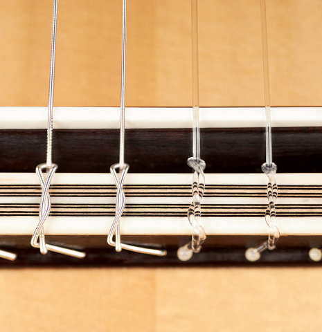The bridge, tie-block and saddle of a 2023 Teodoro Perez "Antigua" classical guitar made of spruce and Indian rosewood.