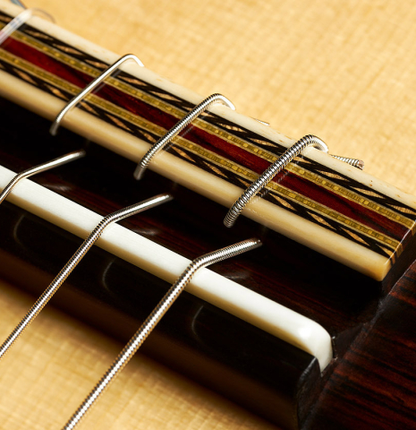 The bridge, tie-block and saddle of a 2023 Erez Perelman classical guitar made of spruce and birdseye maple