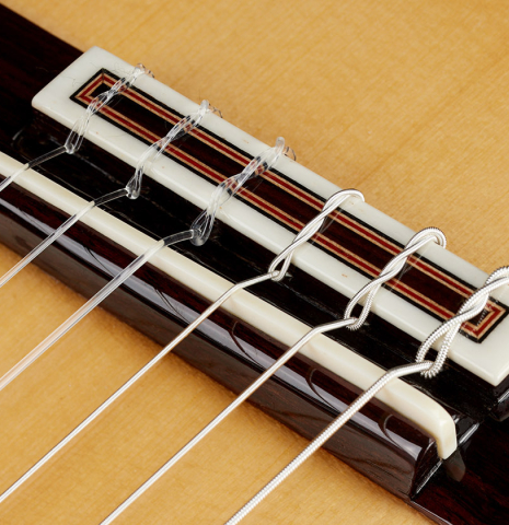 The bridge, tie-block and saddle of a 2024 Sergio Perez "Segovia" classical guitar made of spruce and Indian rosewood.