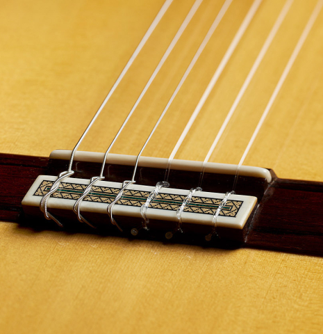 The bridge, tie-block and saddle of a 2024 Teodoro Perez "Especial" classical guitar made of spruce and maple