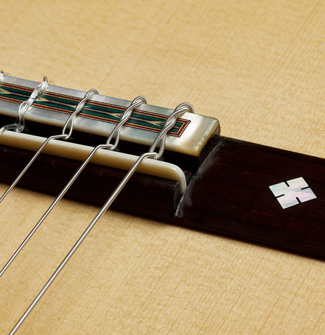 The bridge, tie-block and saddle of a 2024 Teodoro Perez "1884 Torres - La Emperatriz" classical guitar made of spruce and African rosewood