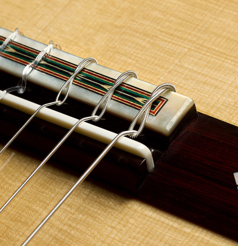 The bridge, tie-block and saddle of a 2025 Teodoro Perez "1884 Torres - La Emperatriz" classical guitar made of spruce and African rosewood