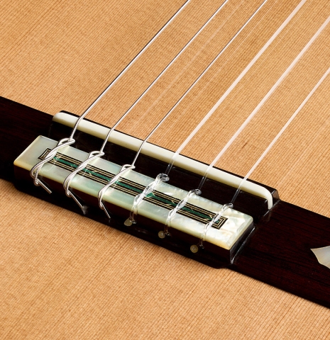 The bridge, tie-block and saddle of a 2026 Teodoro Perez "60th Anniversary" classical guitar made of cedar and African rosewood