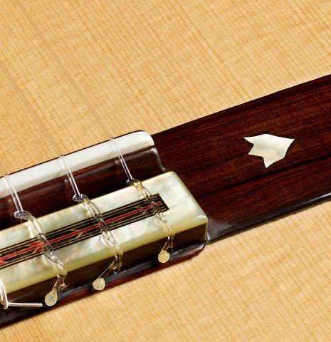 The bridge, tie-block and saddle of a 2026 Teodoro Perez "60th Anniversary" classical guitar made of spruce and pau ferro