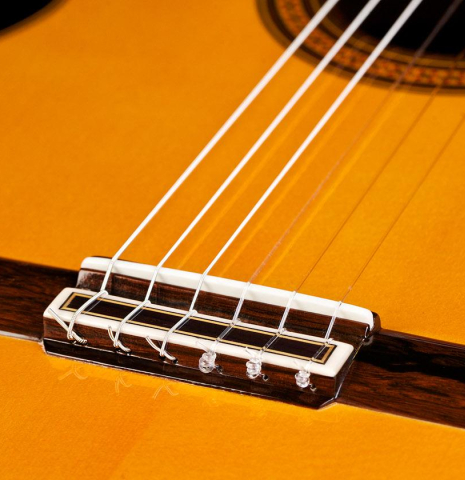 The bridge, tie-block and saddle of a 2016 Jose Ramirez "1a C650-AP" classical guitar made of spruce and CSA rosewood
