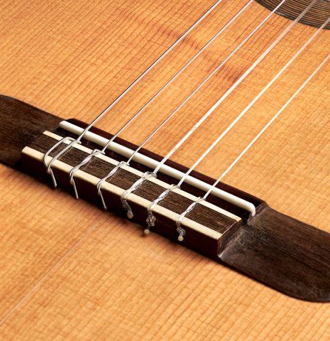 The bridge of a 1910 Jose Ramirez I classical guitar made of spruce and mahogany