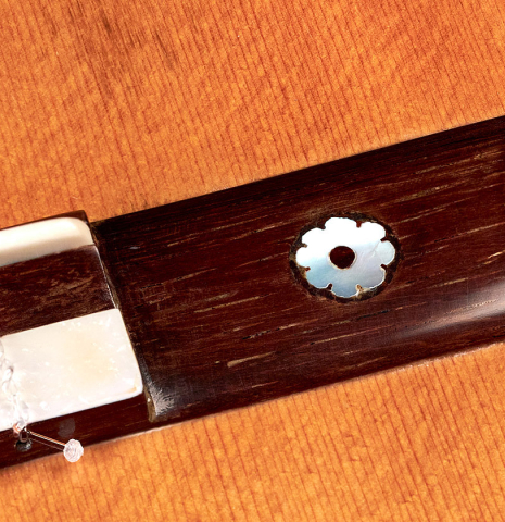 The bridge ornament of a 1912 Manuel Ramirez classical guitar made of spruce and CSA rosewood