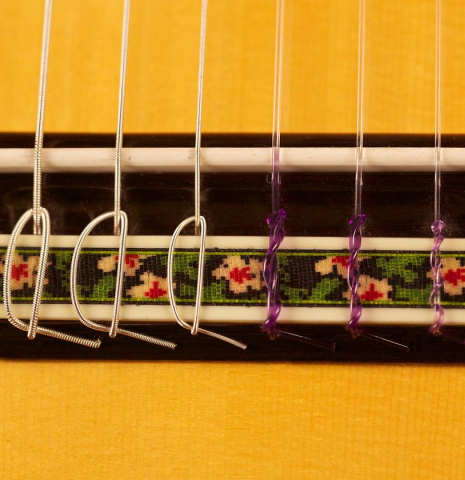 This is a close-up of the bridge, tie-block and saddle of a Jose Ramirez "130 Anos" classical guitar built in 2014. It has a spruce soundboard and Indian rosewood back and sides.
