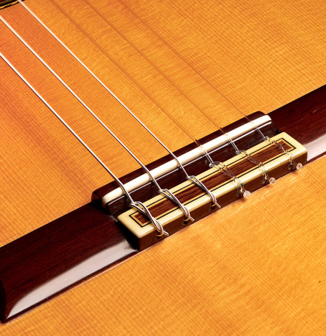 The bridge and nylon strings of a 1988 Jose Ramirez "1a" classical guitar made of spruce and CSA rosewood