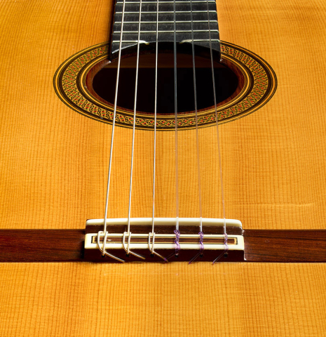 The bridge, tie-block and saddle of a 2004 Jose Ramirez "1a Tradicional" classical guitar made of spruce and Indian rosewood