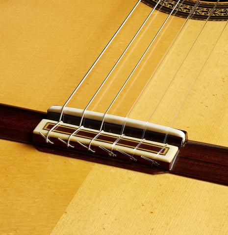 The bridge, tie-block and saddle of a 2013 Jose Ramirez "1a Antigua" classical guitar made of spruce and Indian rosewood