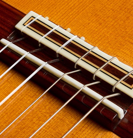 The bridge, tie-block and saddle of a 2023 Jose Ramirez "1a C650" classical guitar made of cedar and Indian rosewood