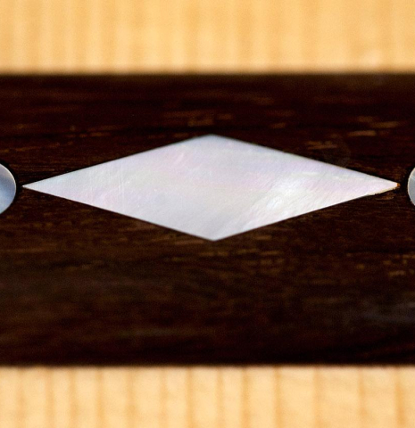 The close-up of the ornamented bridge of a 2010 John Ray "Torres" classical guitar made with spruce and CSA rosewood