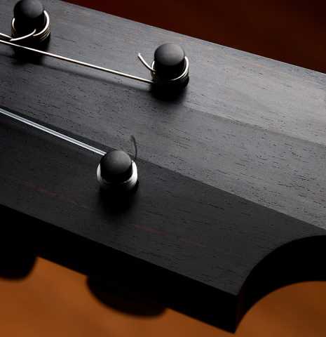 The carved headstock veneer of a 2024 Richard Reynoso w/pegs classical guitar made of spruce and Indian rosewood