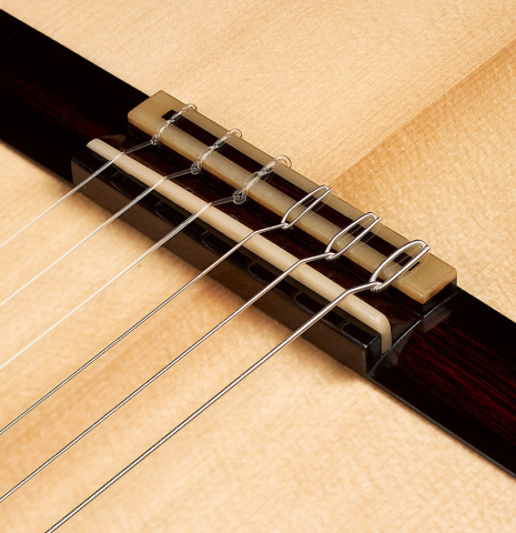 Closeup of the bridge, tie-block and saddle of a 2023 Jean-Noel Rohe classical guitar made of spruce and CSA rosewood