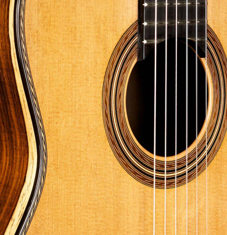 The close-up photo of the front and side of a 2015 Pepe Romero "Centenario" classical guitar made with cedar soundboard and CSA rosewood back and sides