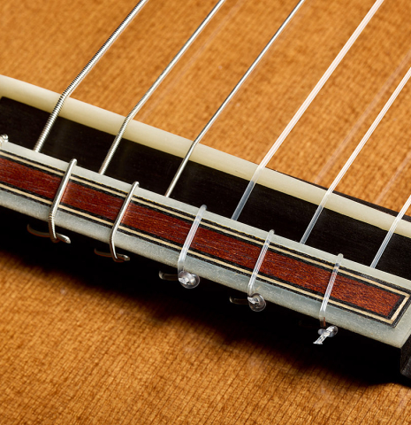 The bridge, tie-block and saddle of a 2025 Pepe Romero classical guitar made of cedar and African rosewood