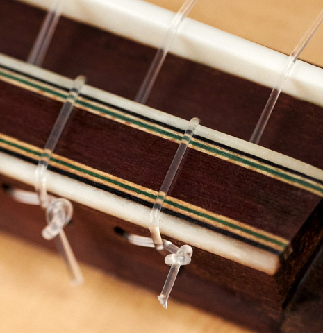 The tie block and bridge of a 2022 Pepe Romero classical guitar made of spruce and CSA rosewood.