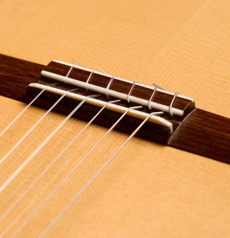 The bridge and saddle of a 2006 Pepe Romero classical guitar made of spruce and CSA rosewood
