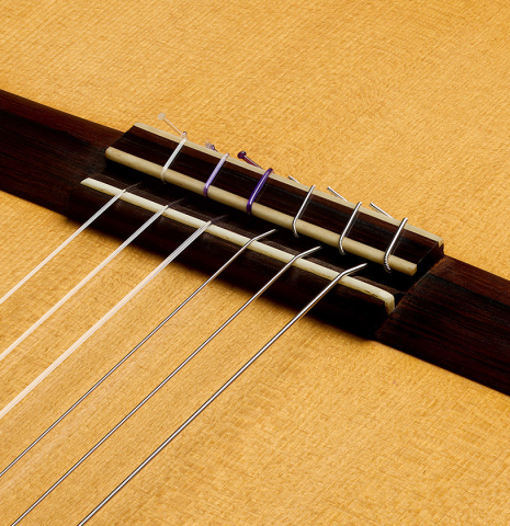 The bridge, tie-block and saddle of a 2006 Pepe Romero classical guitar made of spruce and cypress
