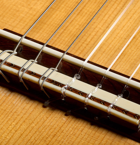 The bridge, tie-block and saddle of a 1981 Jose Romanillos "La España" classical guitar made of spruce and Indian rosewood