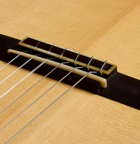 The bridge, tie-block and saddle of a 2021 Pepe Romero "640" classical guitar made of spruce and cypress