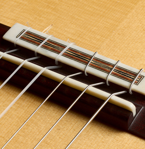 The bridge, tie-block and saddle of a 2018 Jean Rompre classical guitar made of spruce and Makassar ebony