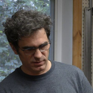 Jean Rompré in glasses and a grey T-shirt in his workshop