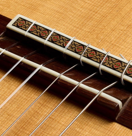 The bridge, tie-block and saddle of a 1999 Ignacio Rozas classical guitar made of spruce and maple