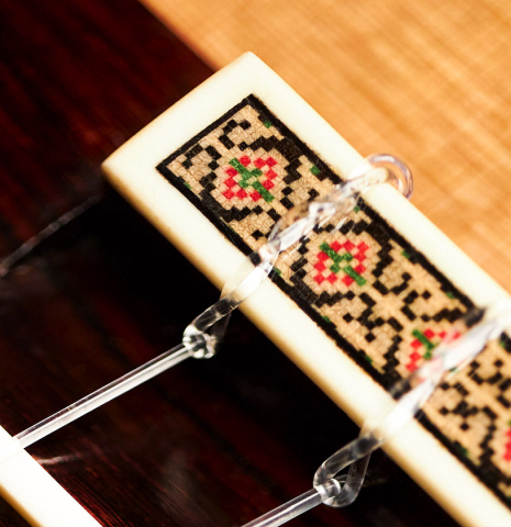 The bridge, nylon strings, and saddle of a 2001 Ignacio Rozas classical guitar made of cedar and CSA rosewood