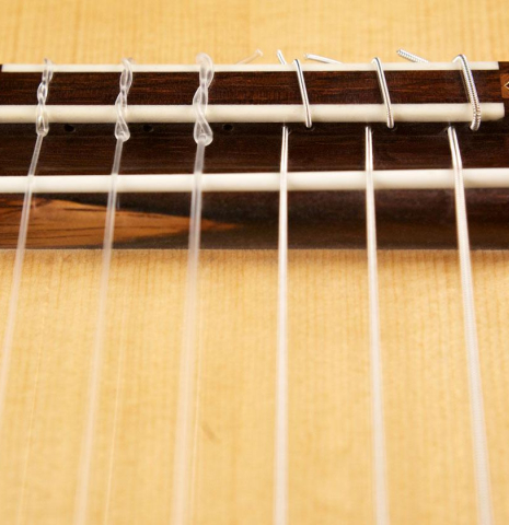 The bridge, tie-block and saddle of a 2007 Jochen Rothel classical guitar made of spruce and maple
