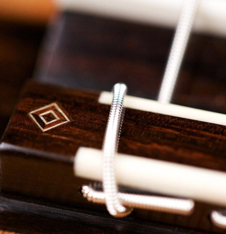 The bridge and saddle of a 2017 Jochen Rothel classical guitar made with cedar and satinwood