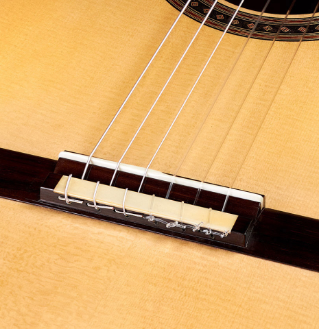 The bridge and saddle of a 2022 Jochen Rothel classical guitar made with spruce top and cherry back and sides